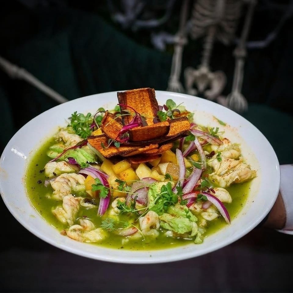 Ceviche with shrimp, red onion, avocado, and sweet potato chips in a green sauce.